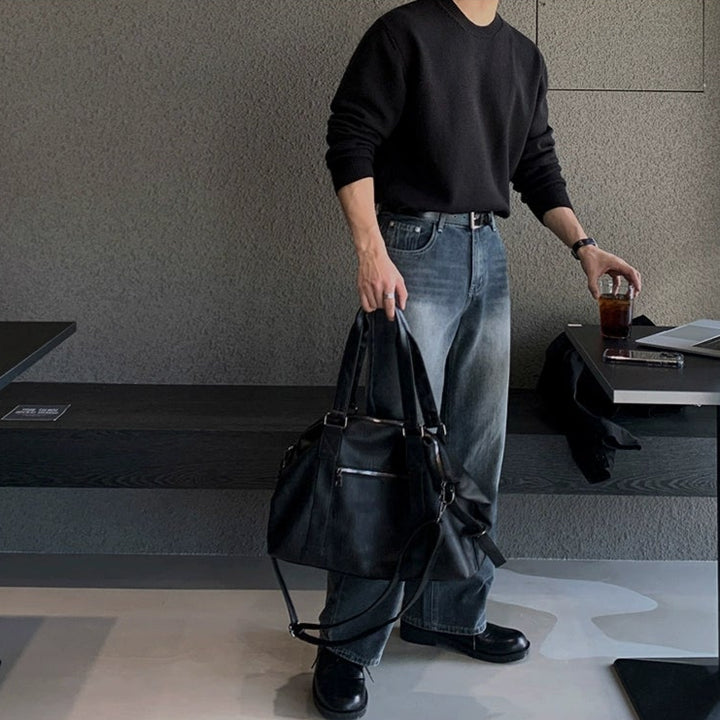 Person holding a black bag in an indoor setting with tables and chairs.